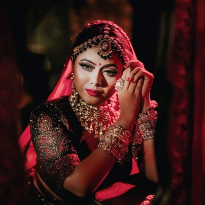 Traditional Indian bridal makeup look with red bridal attire and jewelry at spotlight