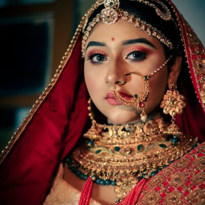 Traditional Indian bridal makeup look with red bridal attire and heavy jewelry”